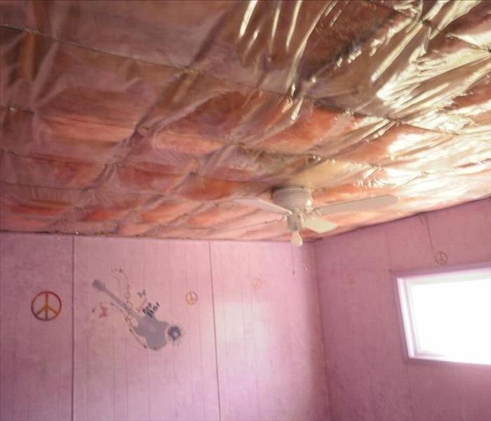 Image of a room with ceiling with a plastic containment and you can see pink insulation thru it. 
