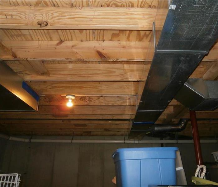 Wood beams in basement ceiling after being restored from water heater damage