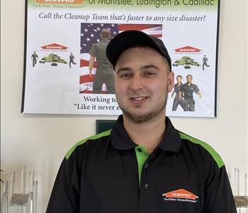 Picture of Elijah Shively smiling in a SERVPRO Hero polo shirt in front of a SERVPRO poster