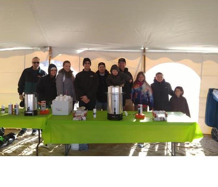 Individuals from the company with family in text in front of table where they served coffee and hot cocoa