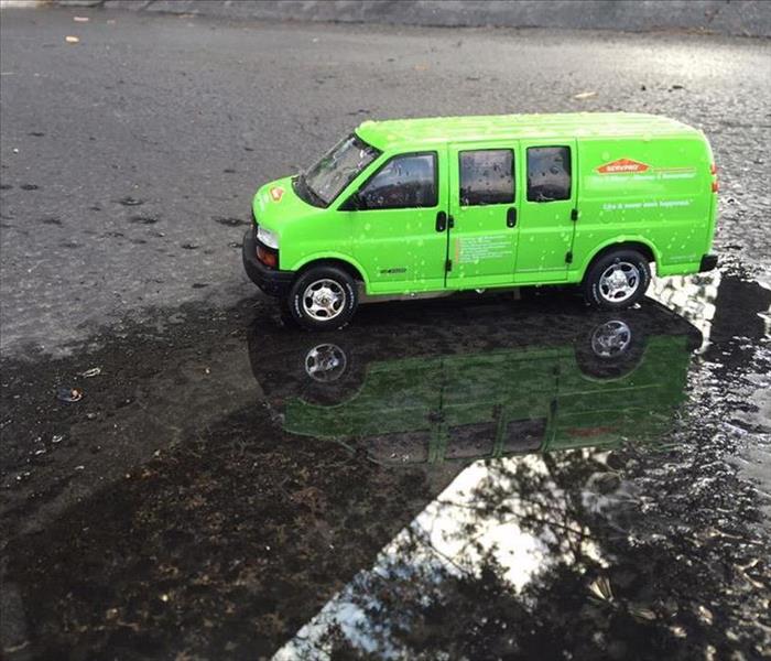 A SERVPRO van parked on puddle of water and rain falling