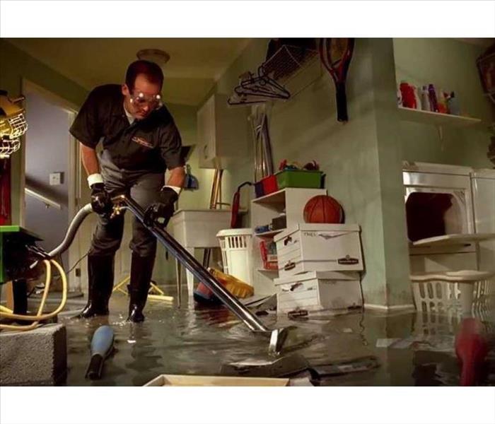 image of a flooded basement with items floating and a SEVPRO technician removing water